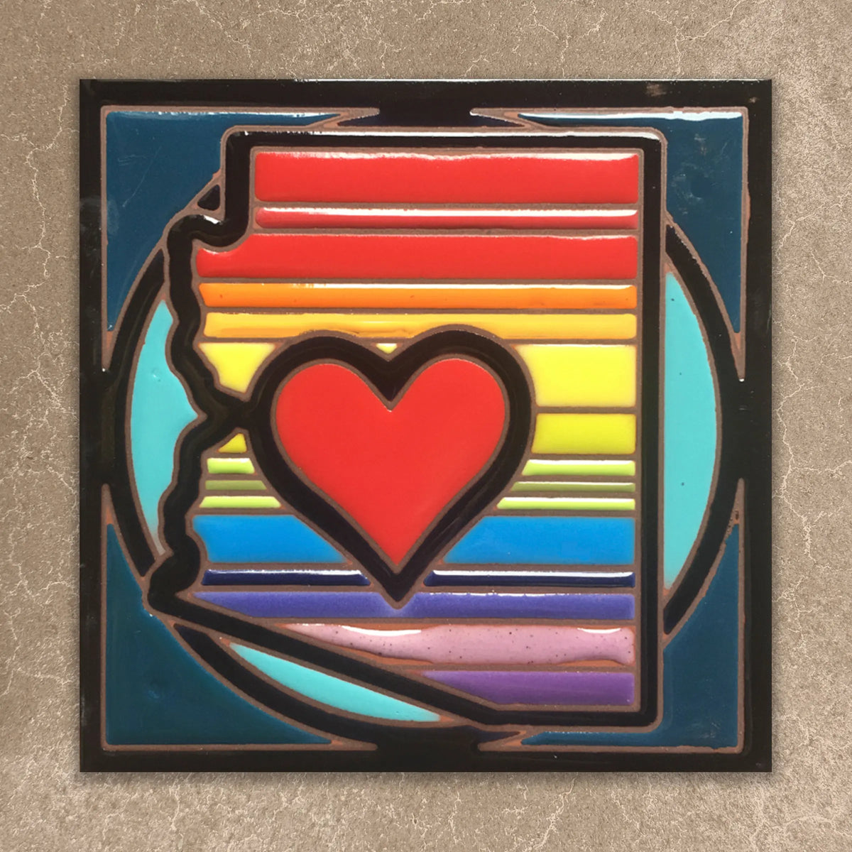 ceramic tile with a red heart and rainbow stripes on a textured surface
