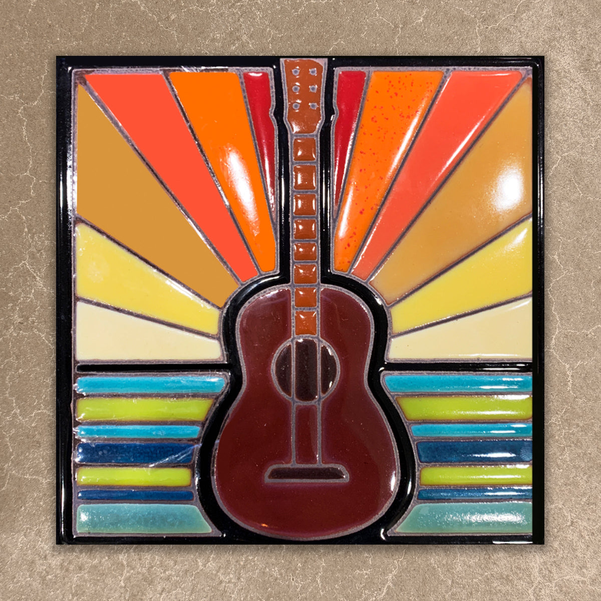 Colorful guitar-shaped object with a sunburst pattern on a beige background