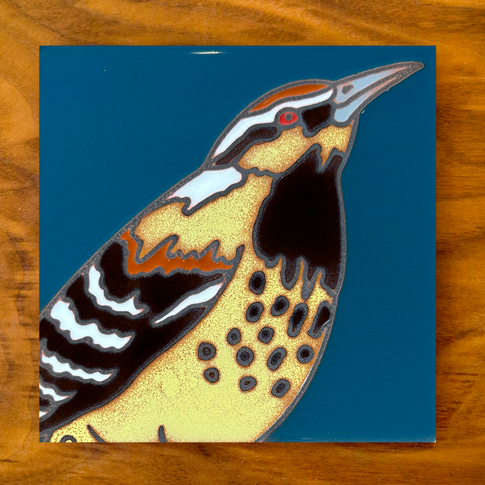 owl ceramic tile coaster on a blue background with wood table