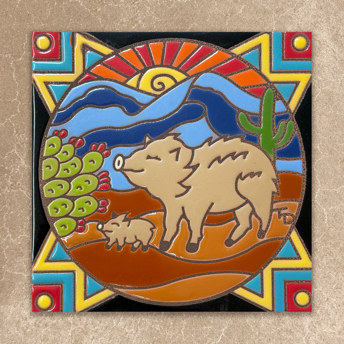 Decorative tile with a javelina and cub design on a colorful geometric background