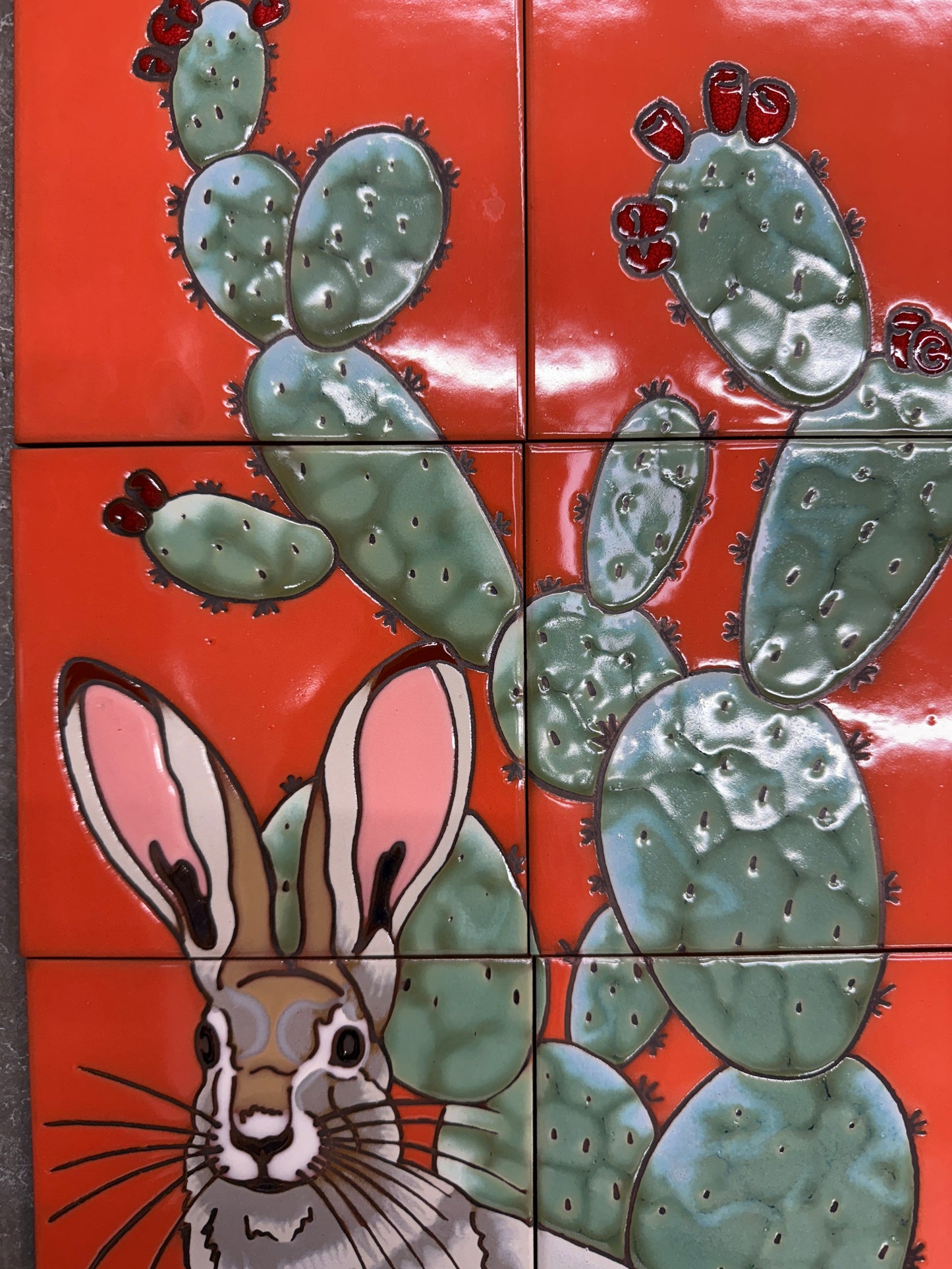 Tile mosaic with a rabbit and cacti on an orange background