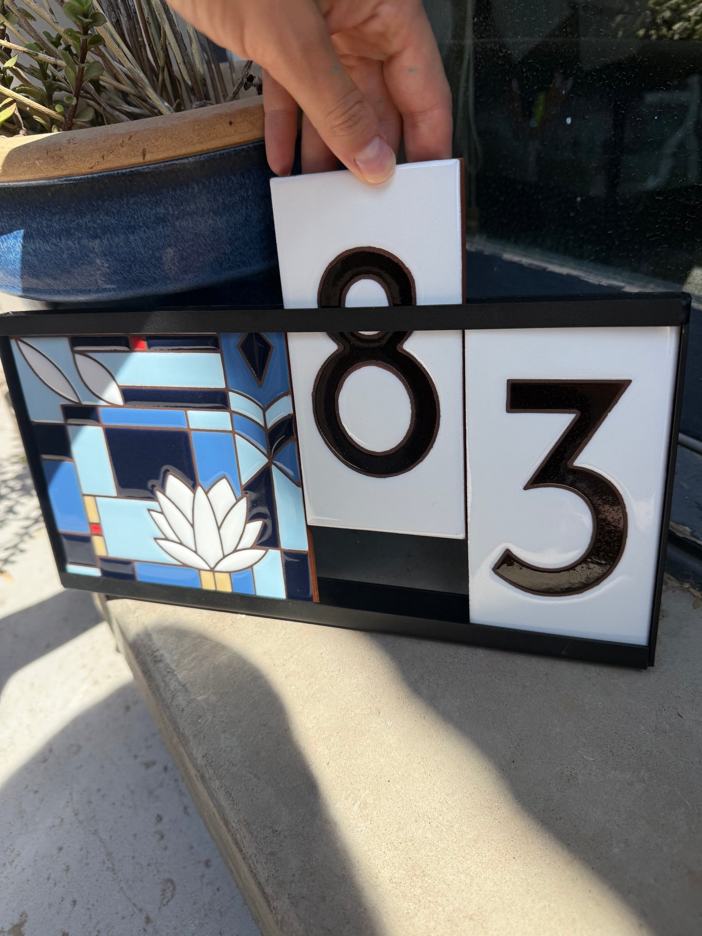 Decorative house number sign with stained glass design and numbers '83'.