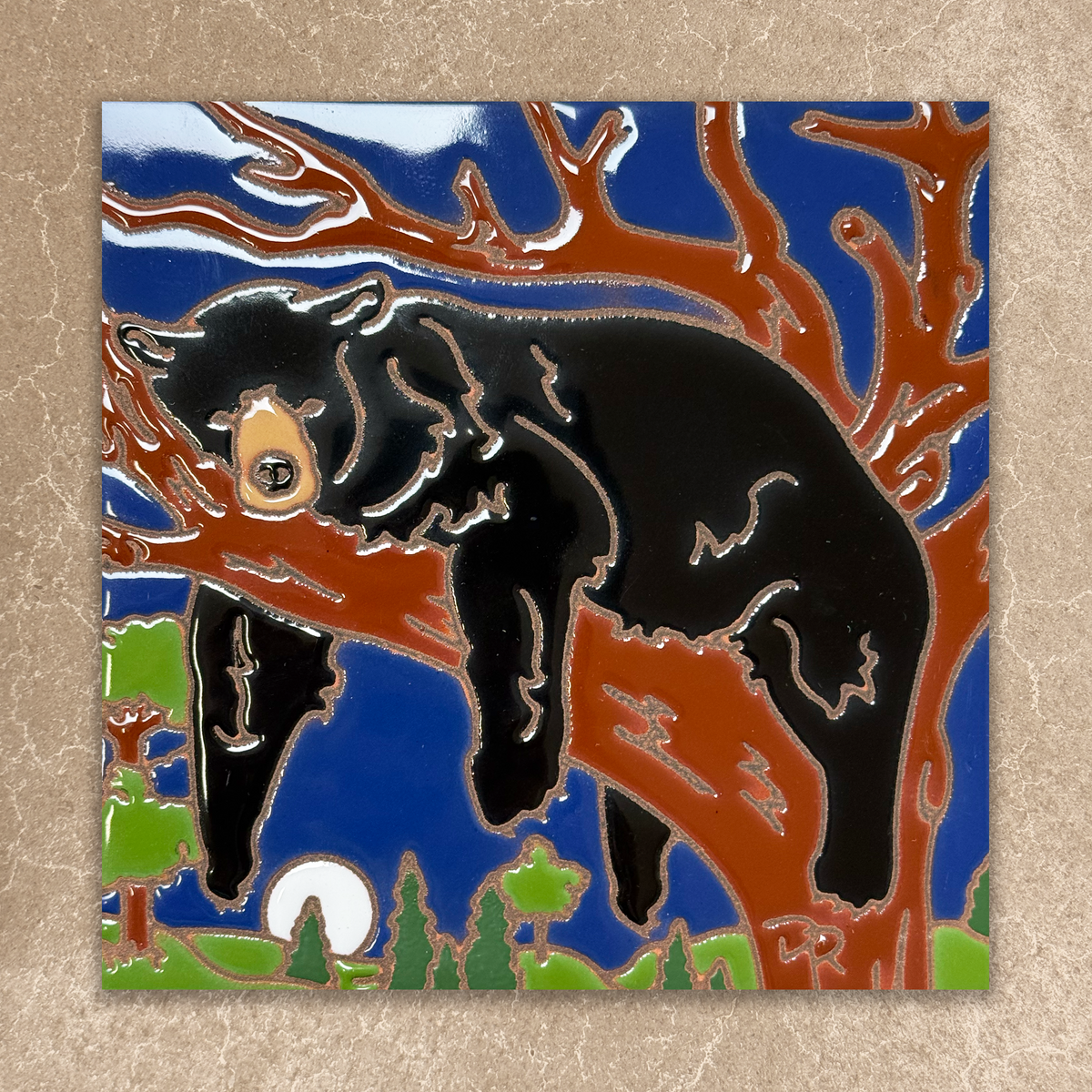 ceramic tile with a black bear climbing a tree against a blue sky.