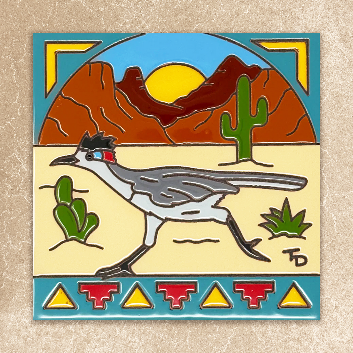 Decorative tile with a desert scene featuring a bird, cacti, and mountains.