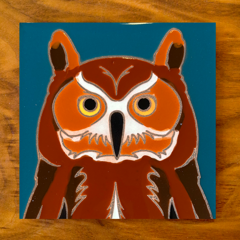 owl ceramic tile coaster on a blue background with wood table
