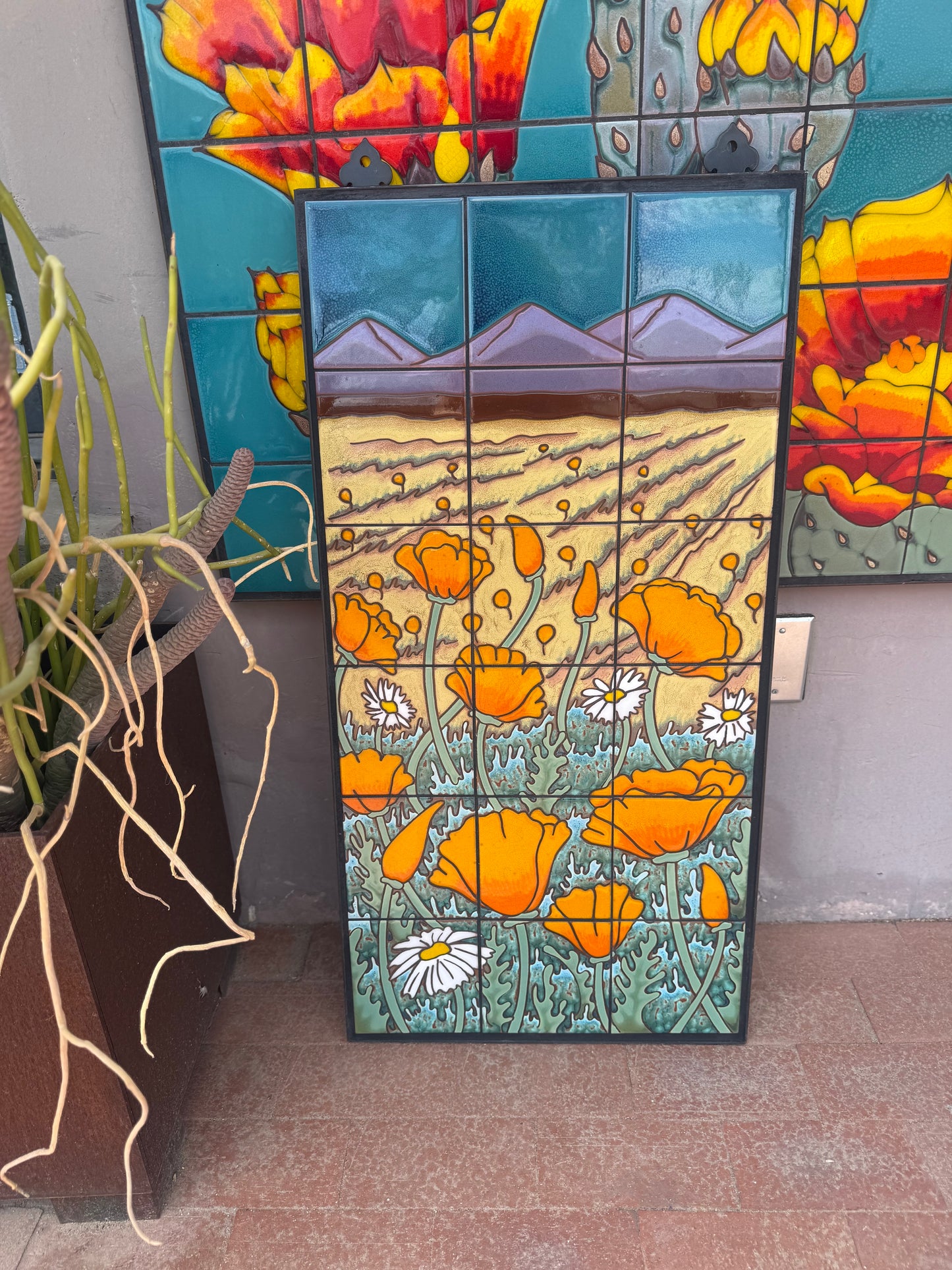 Mosaic artwork with orange flowers and mountains on a wall ceramic tile panel wall art with orange poppy flowers and mountains on a textured wall.