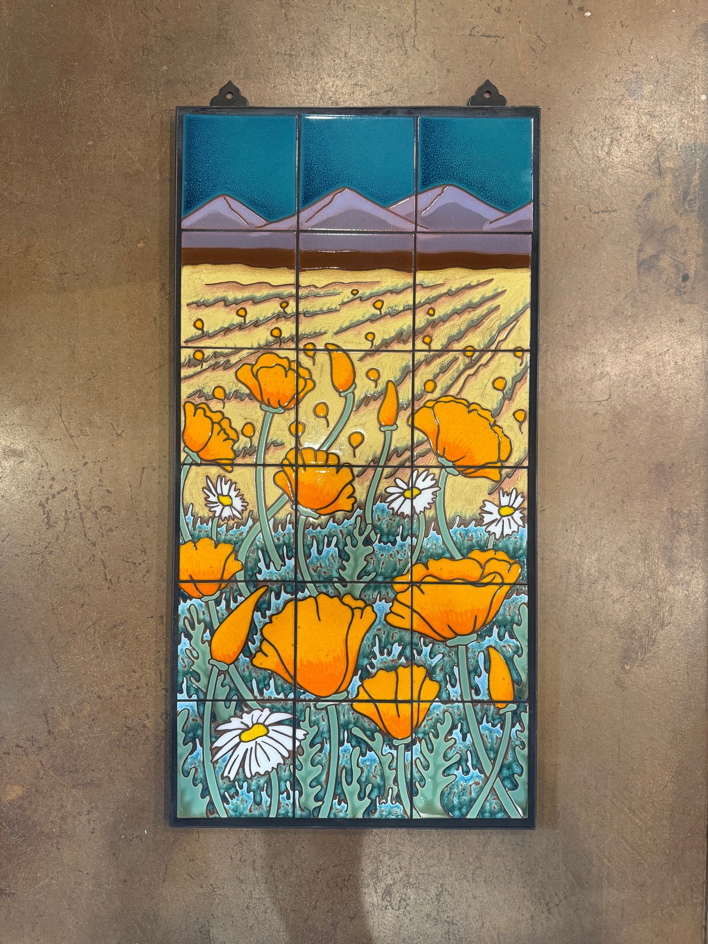 ceramic tile panel wall art with orange poppy flowers and mountains on a textured wall.