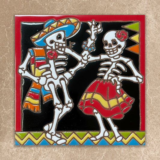 Two skeletons dancing, one in a colorful outfit and the other in a red dress, on a decorative background.