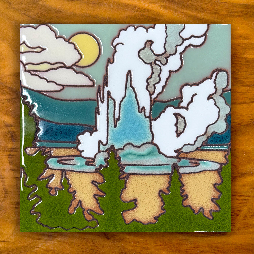 Decorative yellowstone old faithful geyser tile with a stylized landscape featuring trees, clouds, and a moon on a wooden surface.
