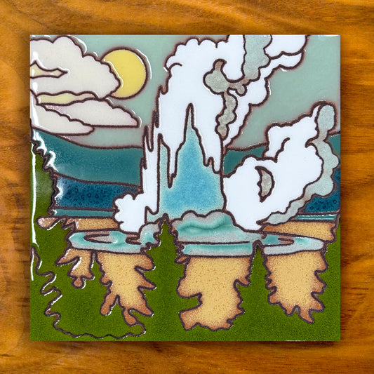 Decorative yellowstone old faithful geyser tile with a stylized landscape featuring trees, clouds, and a moon on a wooden surface.