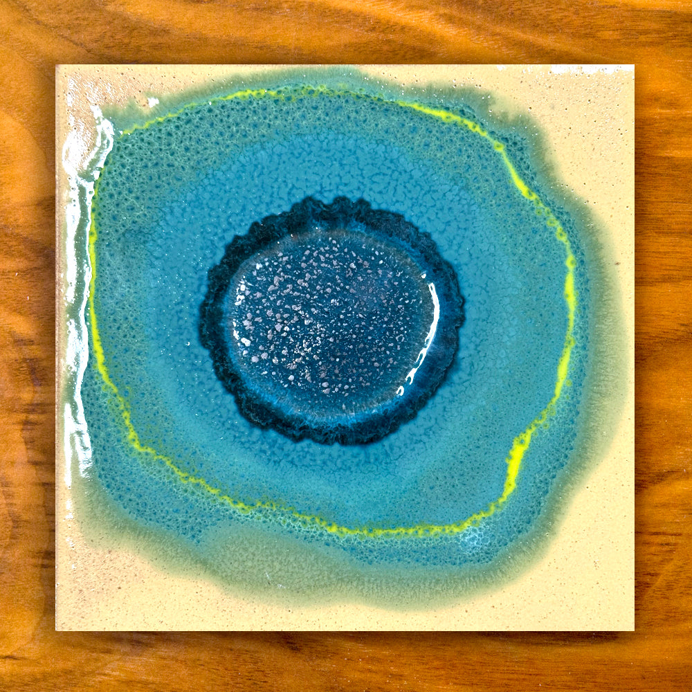 Artistic depiction of a blue and green circular ceramic tile design on a wooden surface