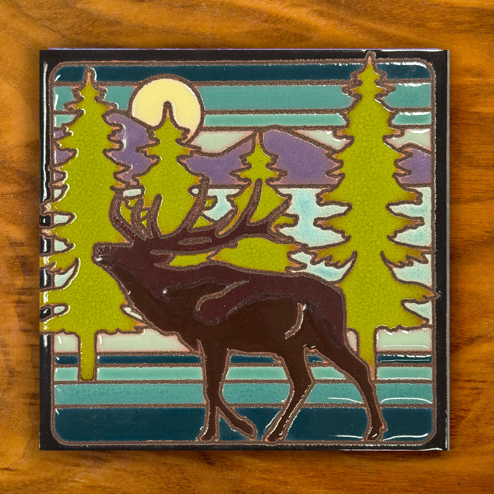 ceramic tile with a deer and forest design on a wooden surface