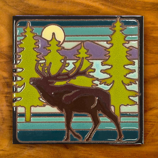 ceramic tile with a deer and forest design on a wooden surface