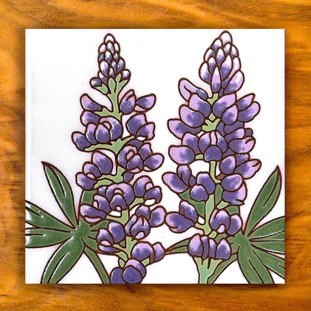 Decorative tile with purple floral design on a wooden surface