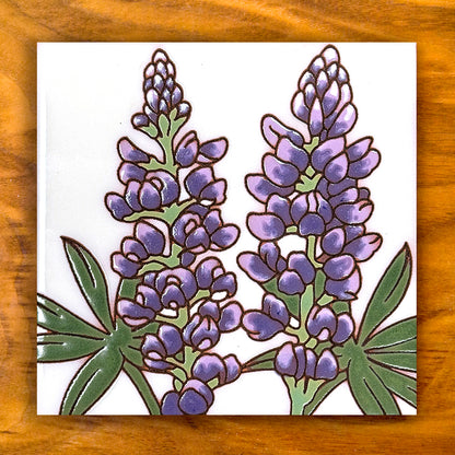 Decorative tile with purple floral design on a wooden surface