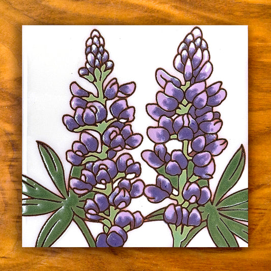Decorative tile with purple floral design on a wooden surface