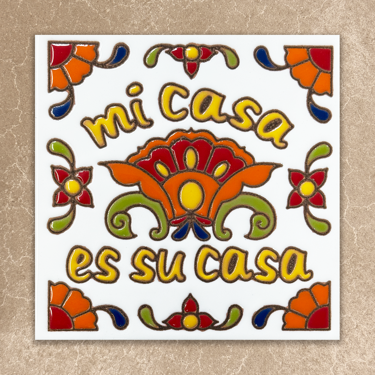 Decorative tile with colorful floral patterns and text 'mi casa es su casa' on a beige background