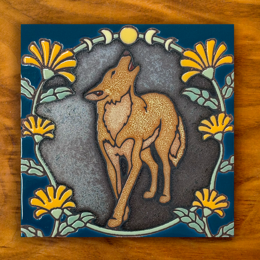 howling coyote ceramic tile on a shimmery black and blue with orange flowers, shown on a wooden background
