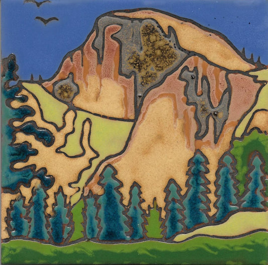 A square ceramic tile featuring a stylized landscape painting of a mountain with pine trees and birds, decorated with metallic gold, green, blue, and terracotta glazes.