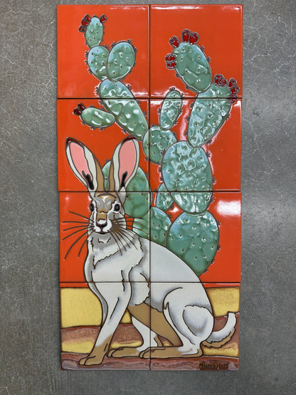 Decorative tile mural with a rabbit and cactus design on an orange background.
