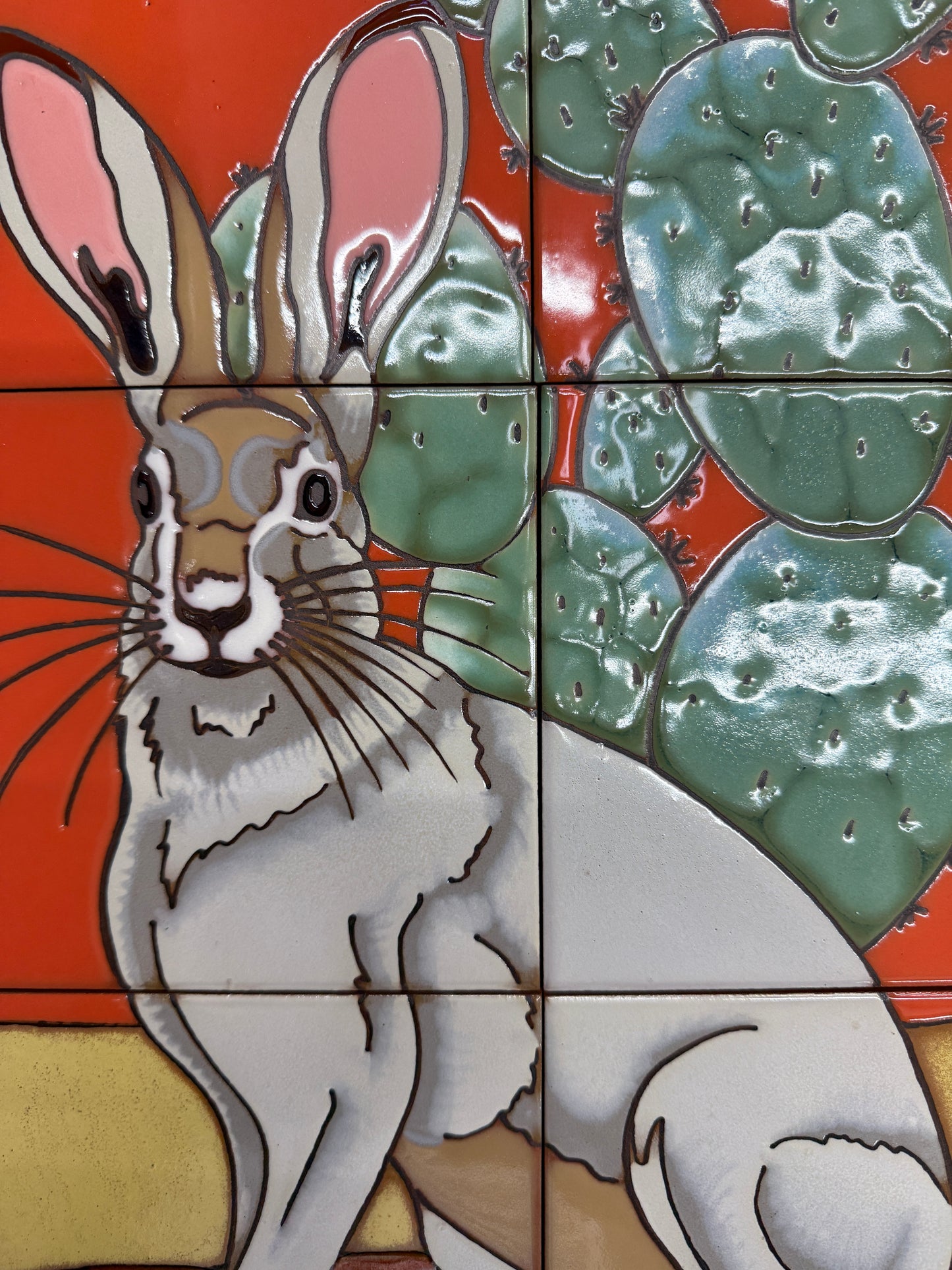 Tile mosaic featuring a stylized rabbit and lily pads on a red background