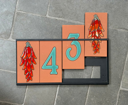 Decorative house number '43' with red chili pepper design on a stone surface