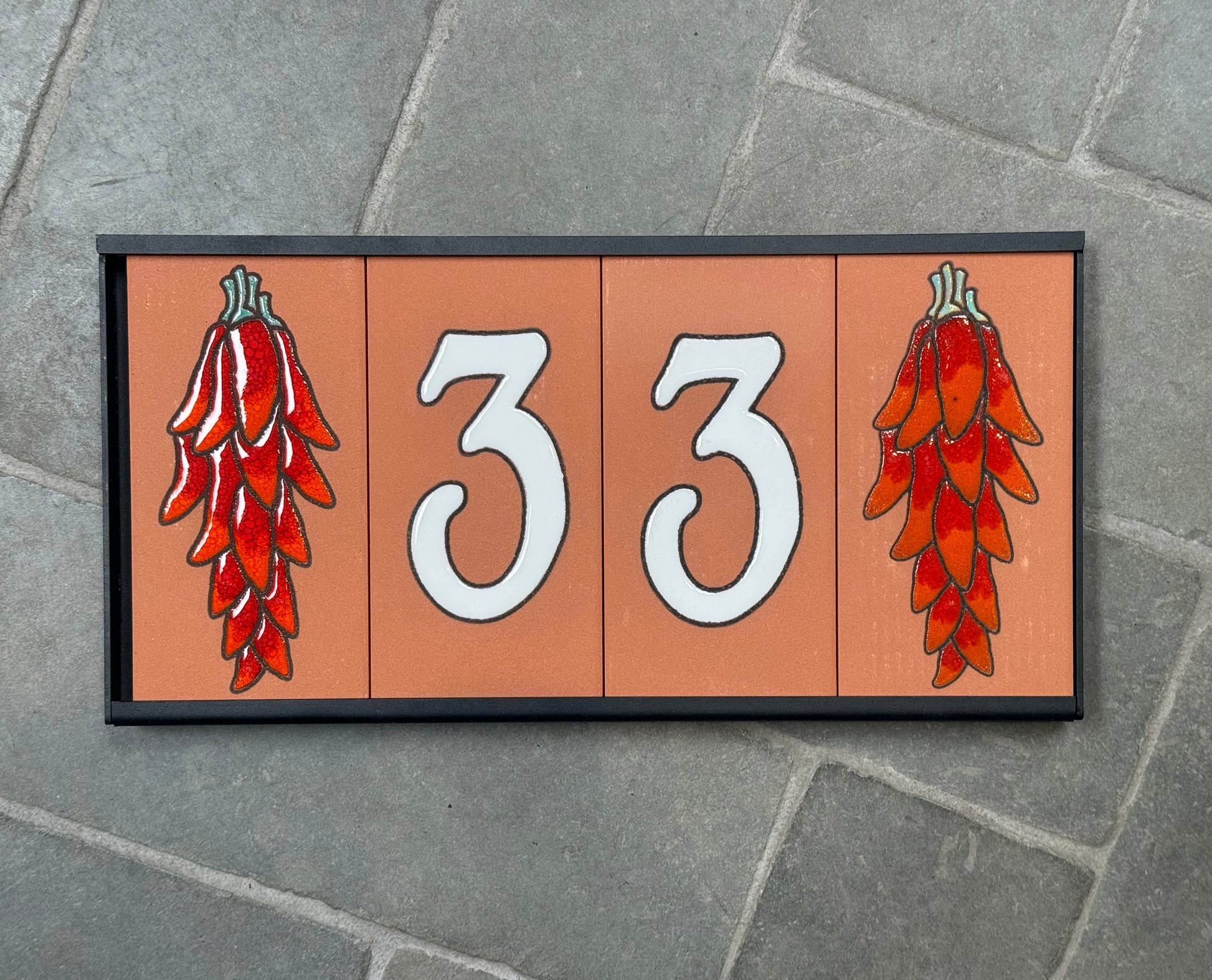 Decorative house number sign with red chili peppers on a stone background