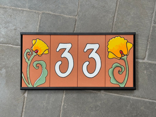 Decorative house number sign with flowers on a stone wall