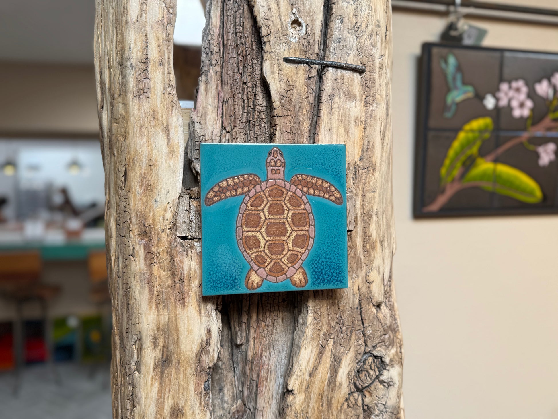 Square tile with a turtle design on a wooden surface