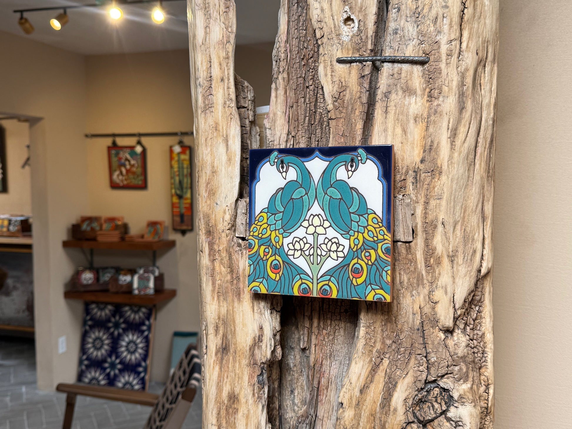 Decorative tile with peacock design on a wooden surface