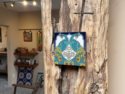 Decorative tile with peacock design on a wooden surface