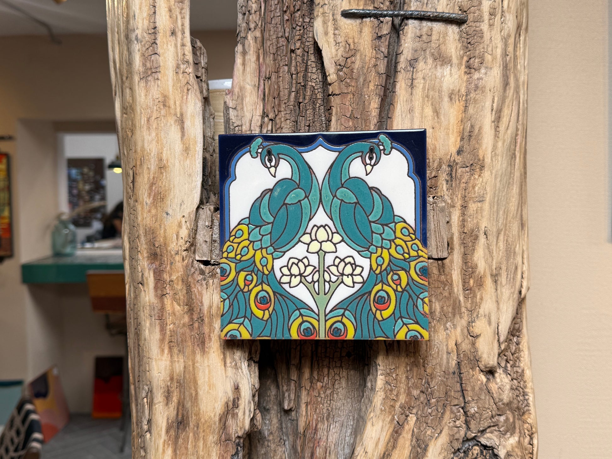 Decorative tile with peacock design on a wooden surface