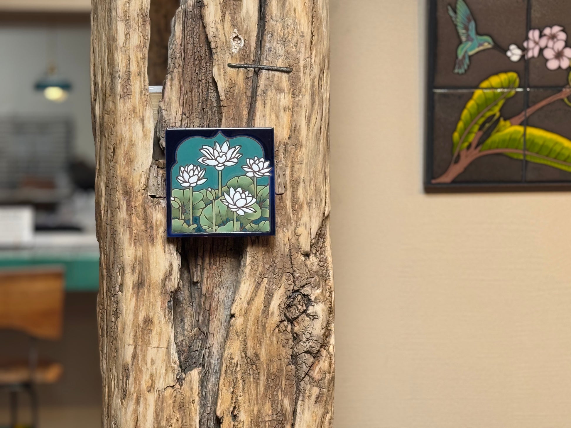 Decorative tile with floral design attached to a wooden surface.