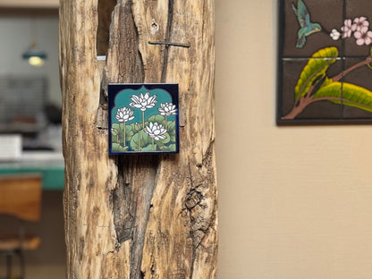 Decorative tile with floral design attached to a wooden surface.