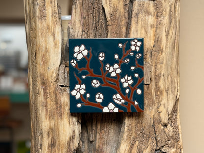 Decorative tile with floral design on a wooden surface