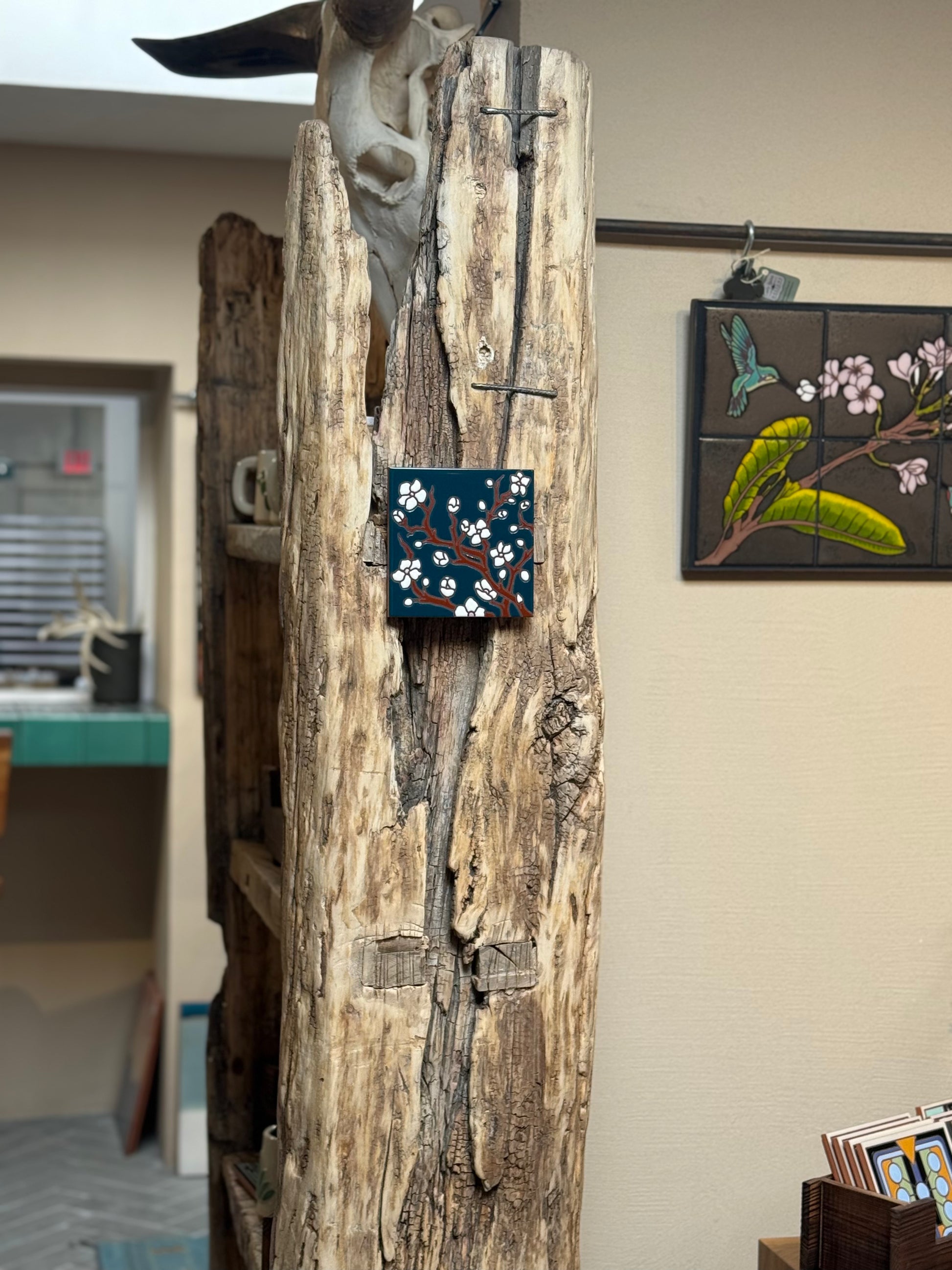 Wooden sculpture with a small painting on a wall in the background