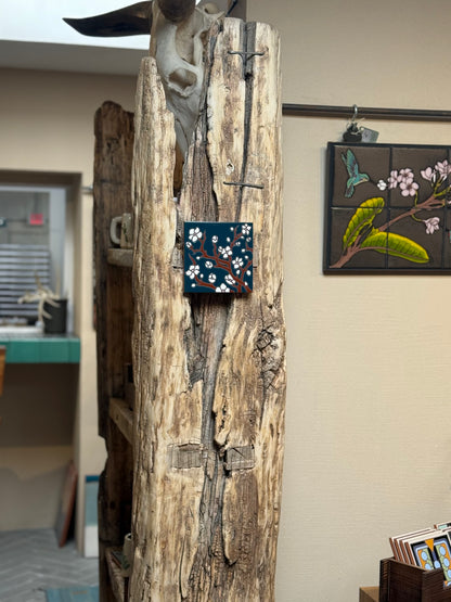 Wooden sculpture with a small painting on a wall in the background