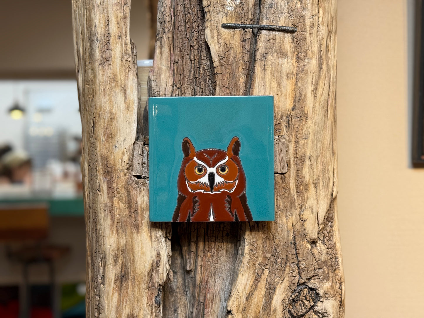 Square tile with an owl design on a wooden surface