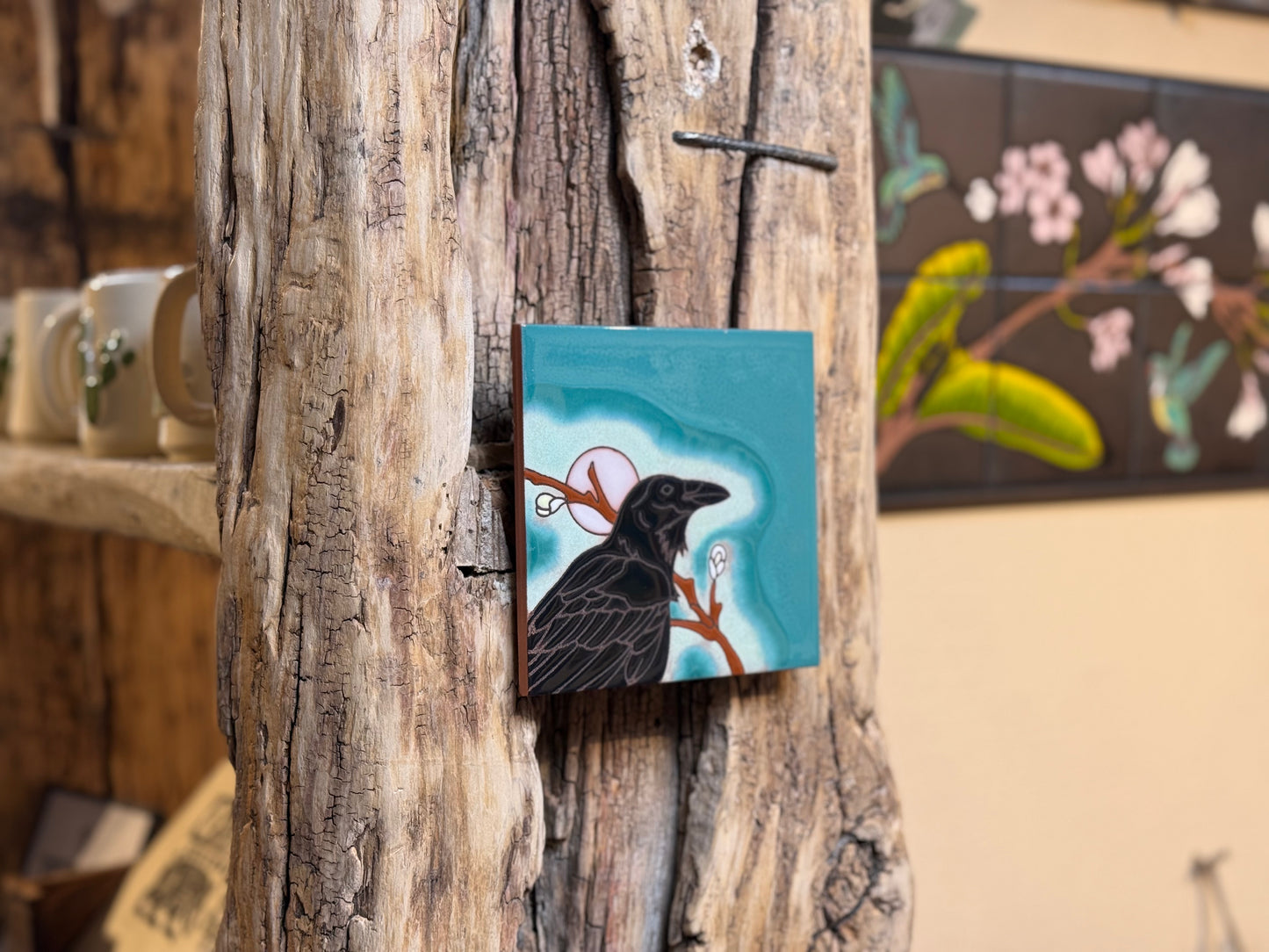Small painting of a bird on a branch attached to a wooden surface.