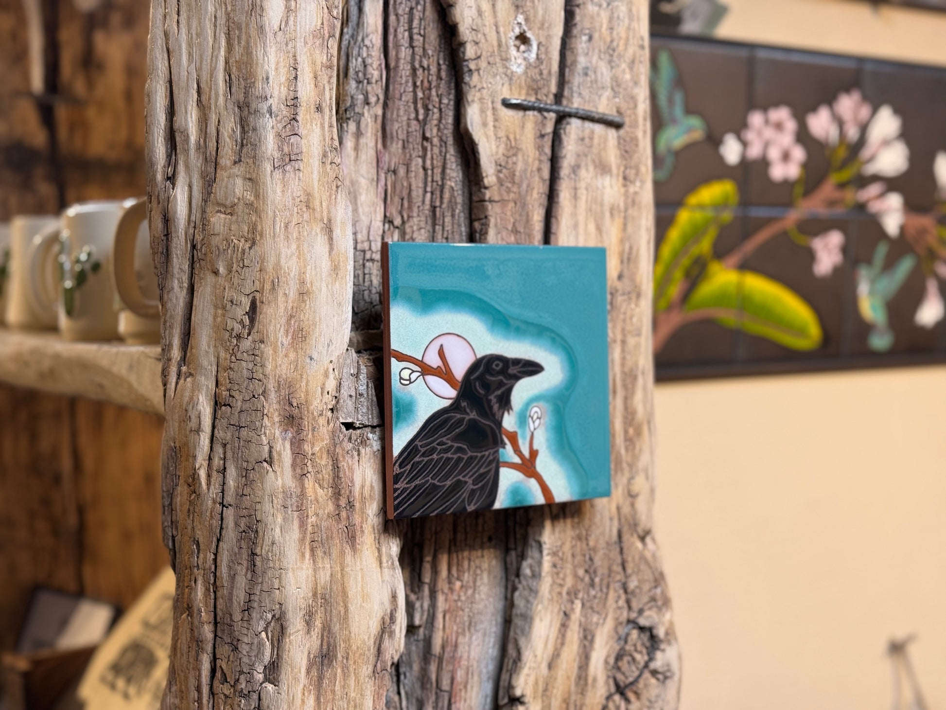 Small painting of a bird on a branch attached to a wooden surface.