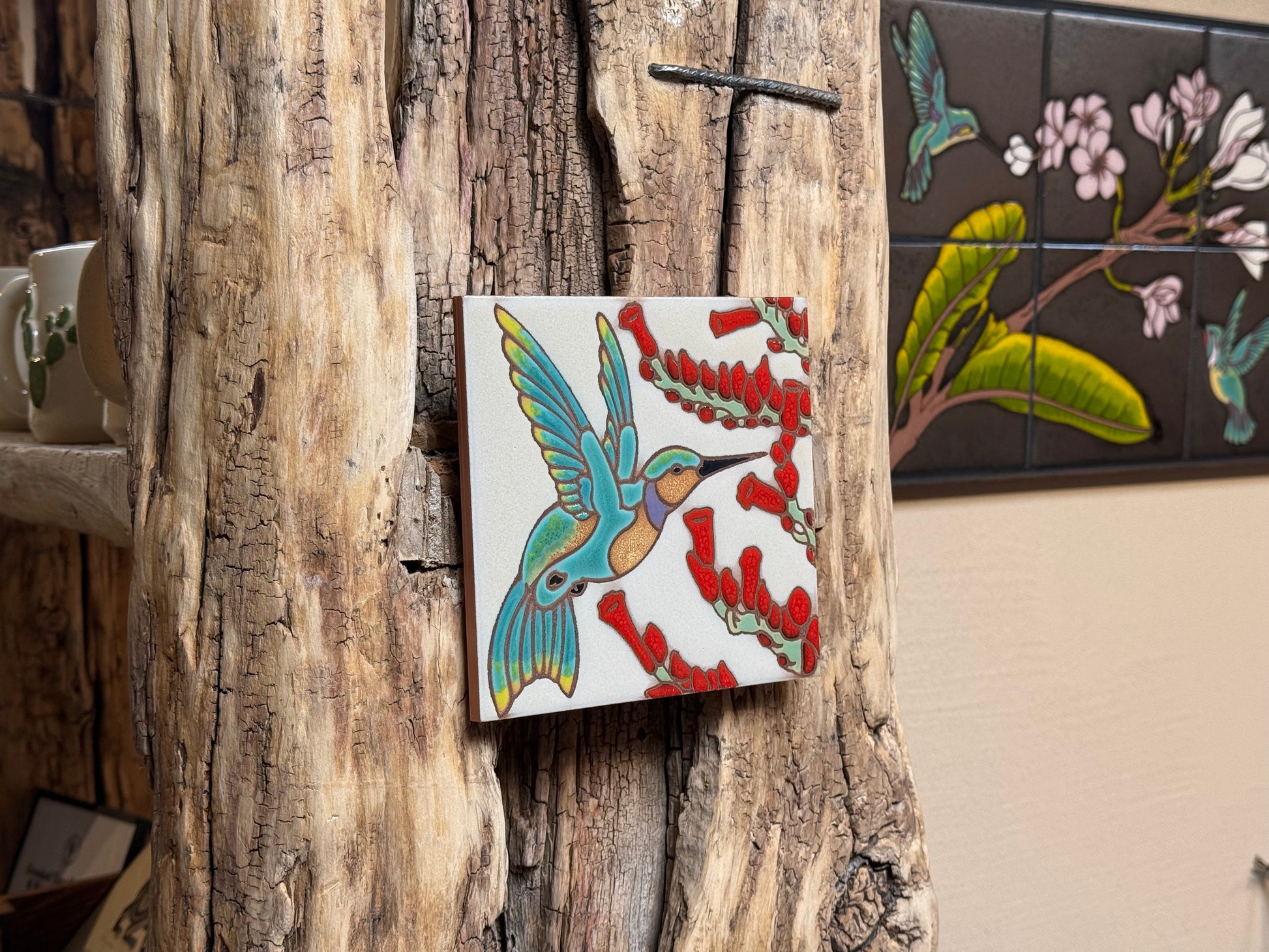Decorative tile with a colorful bird design on a rustic wooden wall.