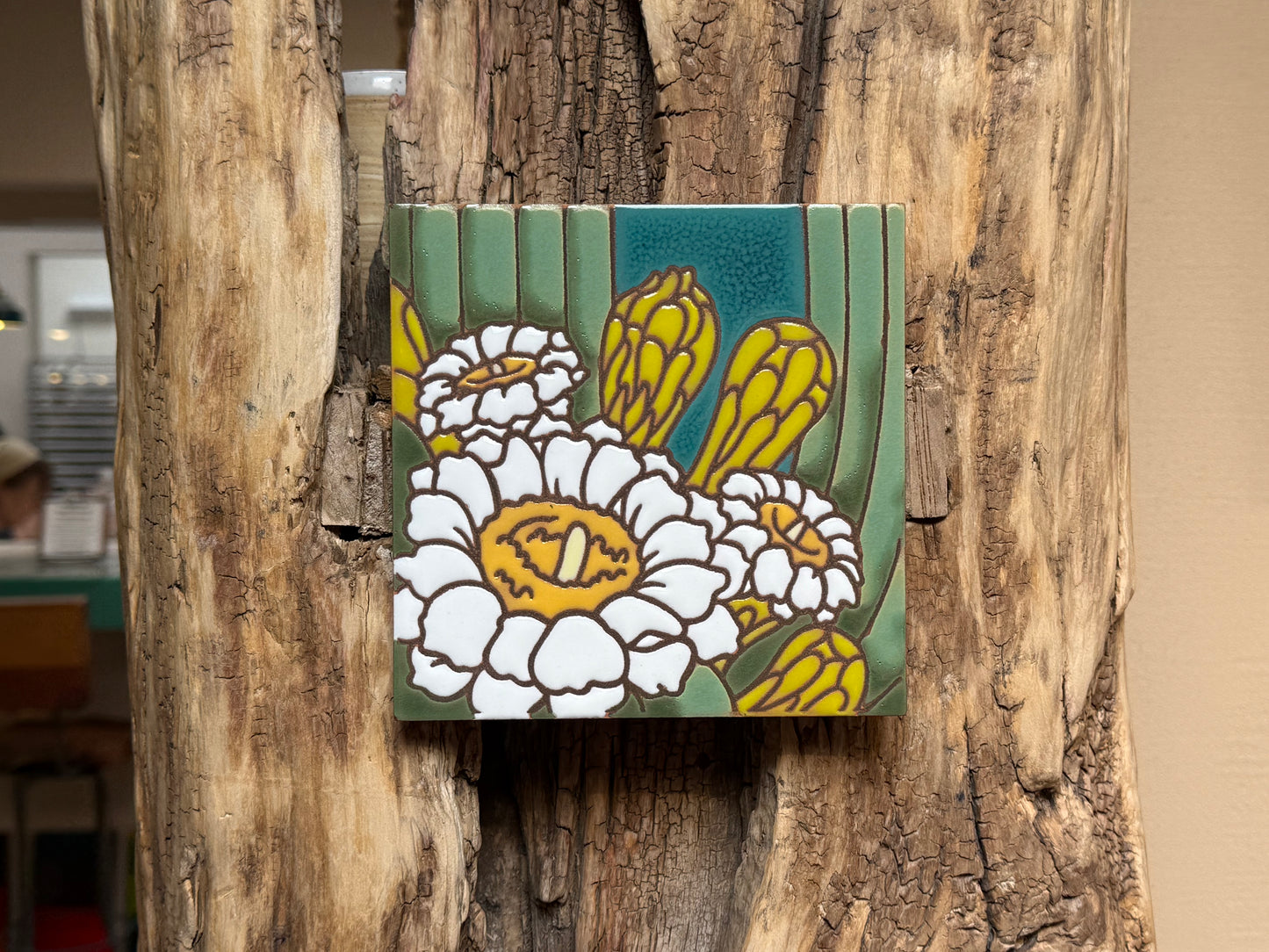 Decorative tile with floral design attached to a wooden surface
