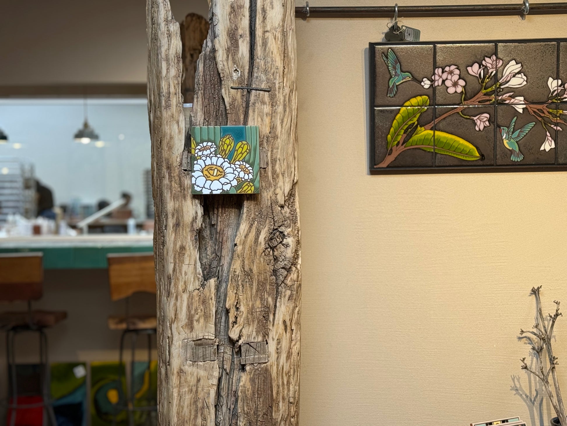 Decorative tiles with floral and bird designs on a wall next to a wooden log.