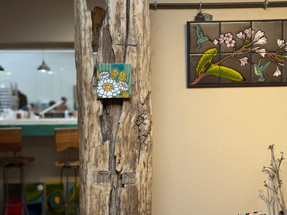 Decorative tiles with floral and bird designs on a wall next to a wooden log.