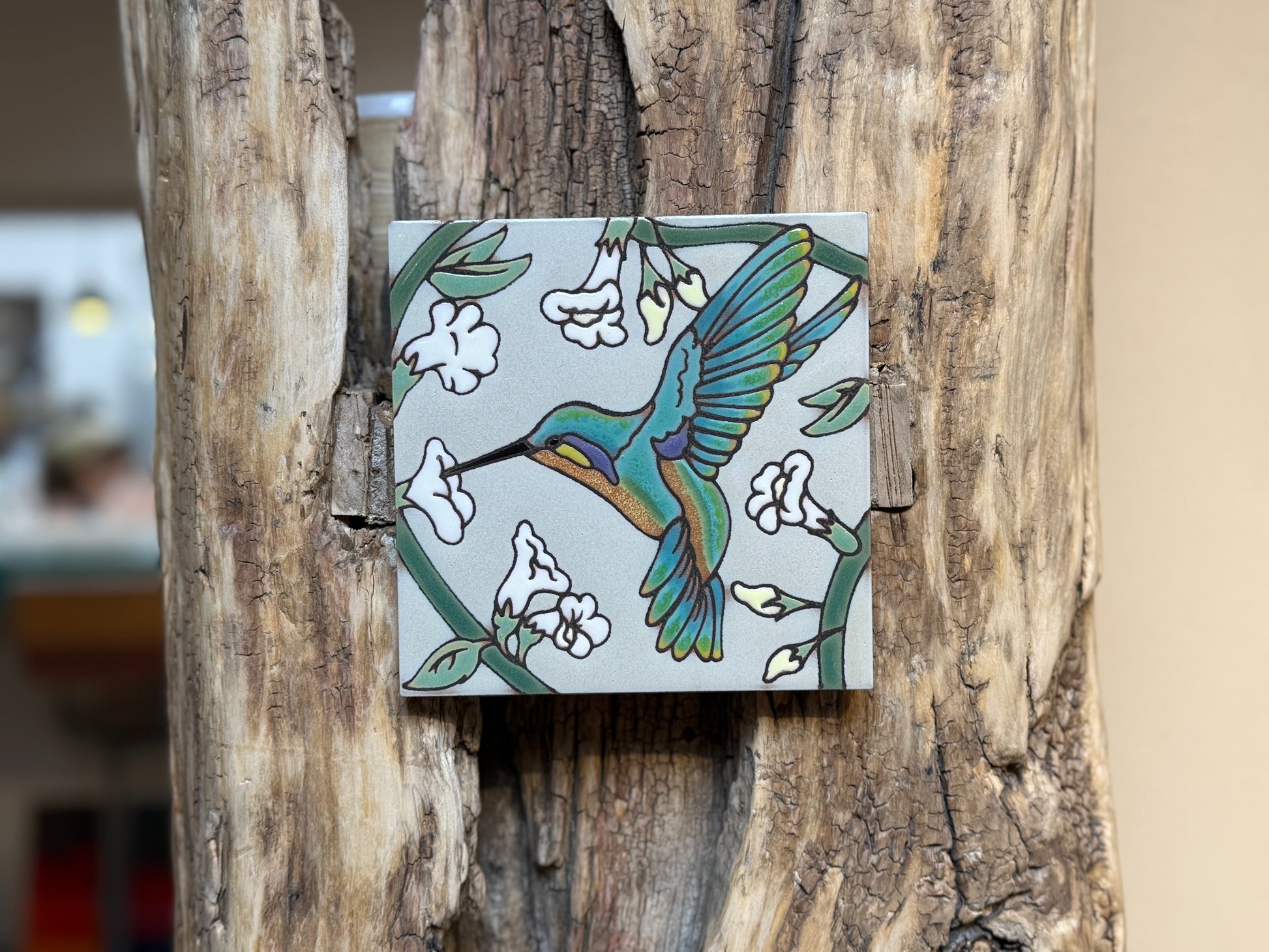 Decorative tile with a colorful bird design on a wooden surface