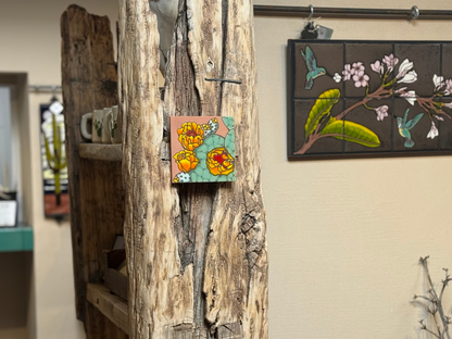 Artistic wall decorations on a textured wall with a wooden shelf.