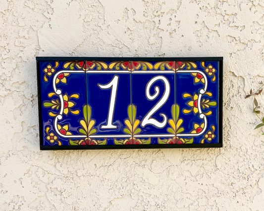 Decorative house number '12' on a textured wall with floral designs