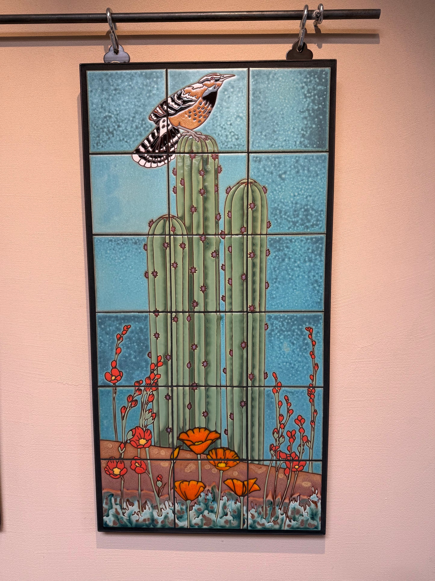 ceramic tile wall art with cactus and bird on blue background