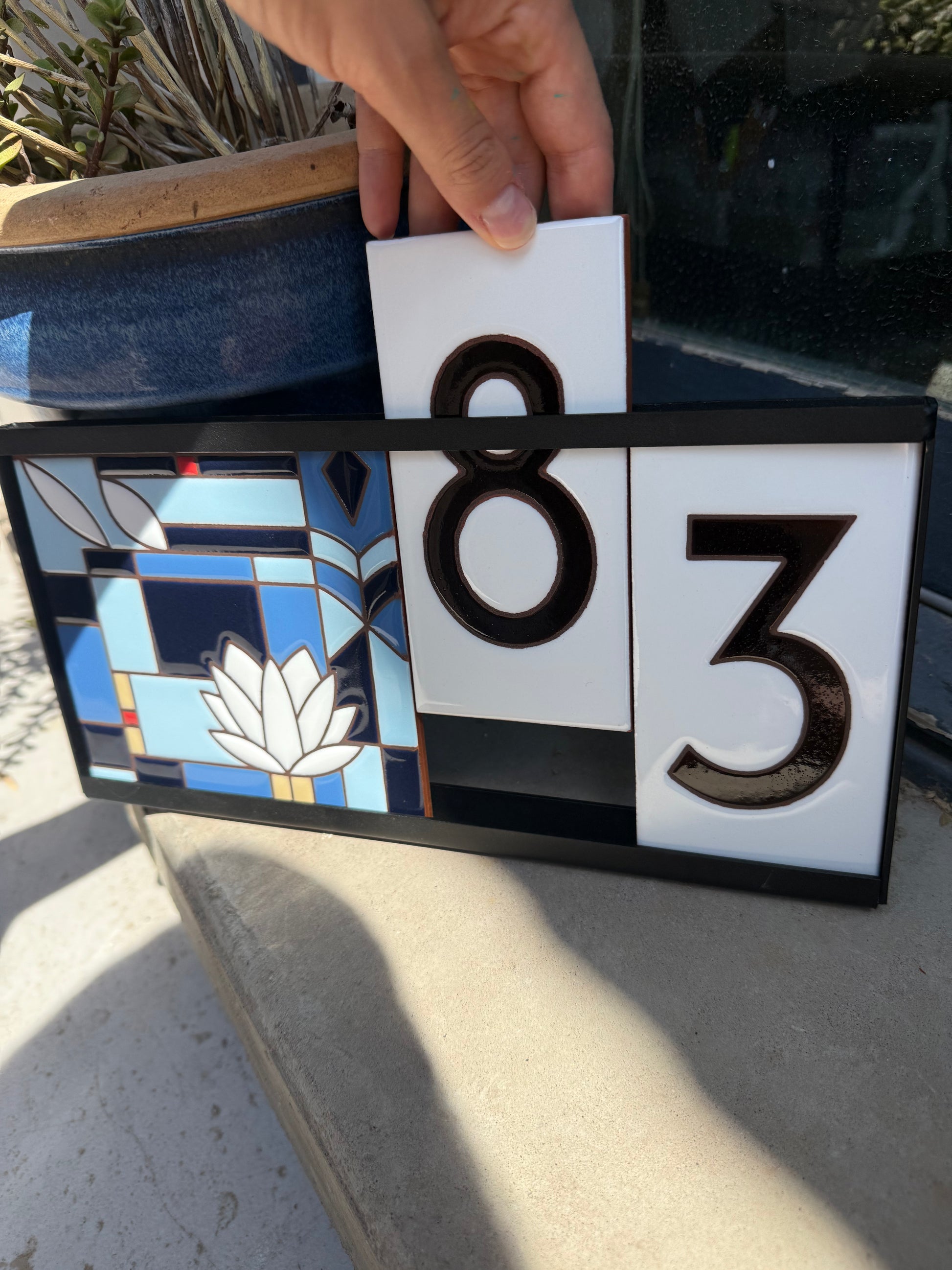 Decorative house number sign with stained glass design and numbers '83'.