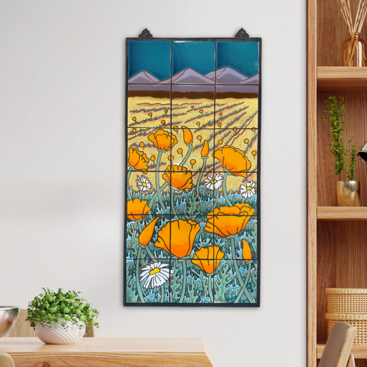 Framed artwork of orange flowers and mountains on a wall above a wooden shelf.